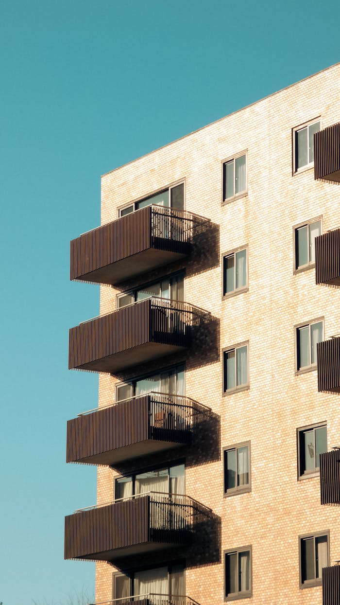 Contemporary brick apartment building with balconies against a clear blue sky.